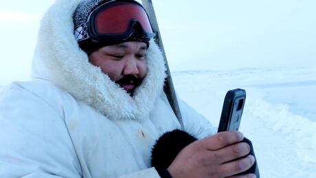Puasi Ippak tests out the Siku mobile app in a handout photo. A social media app geared toward the outdoor lives of Inuit launched Wednesday with features that tie traditional knowledge to smart phone technology. Inuit App