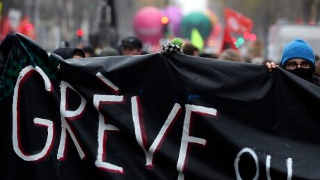 Protesters carry a banner reading "Strike" during a demonstration in Paris, Thursday, Dec. 5, 2019. The Eiffel Tower shut down, France's vaunted high-speed trains stood still and several thousand protesters marched through Paris as unions launched open-ended, nationwide strikes Thursday over the government's plan to overhaul the retirement system. France Strikes