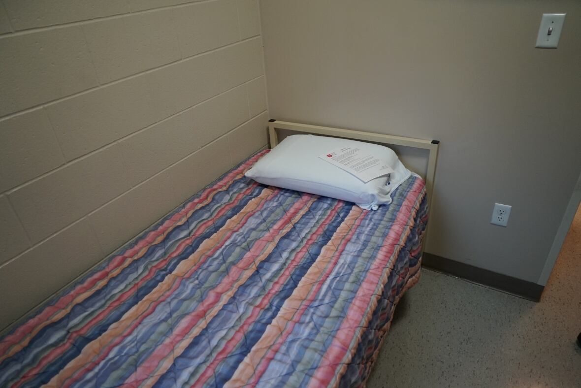 A metal frame bed has a multi-coloured comforter. 