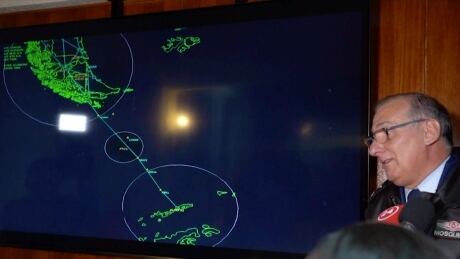 In this image made from video, Gen. Eduardo Mosqueira, right, of the Fourth Air Brigade speaks to the media next to a map of the area where the airplane is missing, in Punta Arenas, Chile, Monday, Dec. 9, 2019. Chile's air force lost radio contact with a transport plane carrying 38 people on a flight Monday evening to the country's base in Antarctica, and authorities indicated several hours later that they were not optimistic about the aircraft's fate. The military said earlier that it had declared an alert and activated search and rescue teams. (AP Photo) Chile Military Plane Missing