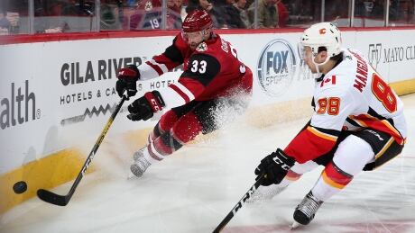 Arizona's Alex Goligoski attempts to play the puck under pressure from Calgary's Andrew Mangiapane during the second period of the Coyotes' 5-2 loss to the Flames on Tuesday. mangiapane-andrew-121019