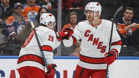 Carolina's Sebastian Aho, left, and Dougie Hamilton, right, celebrate a first-period goal during the Hurricanes' 6-3 win against the Edmonton Oilers on Tuesday. hamilton-aho-121019