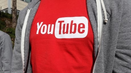 This April 4, 2018, file photo shows a YouTube logo on a t-shirt worn by a person near a YouTube office building in San Bruno, Calif. YouTube is taking another step to curb hateful and violent speech on its site. The video streaming company said it will now take down videos that lob insults at people based on race, gender expression or sexual orientation. YouTube Harassment Policy