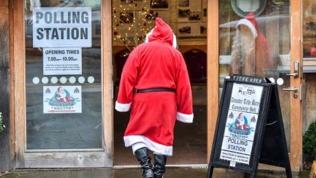 A man dressed as Father Christmas enters his grotto at the Dunster Tithe Barn near Minehead, Somerset, England which is being used as a polling station in the 2019 general election, Thursday Dec. 12, 2019. Britain is holding an early election in wintry December, with a number of strange locations put in use as polling places. Among the places where Britons cast their ballots Tuesday were a car dealership, a laundrette, a Christmas grotto and of course some pubs. There were a few problems, including flooding at one location. (Ben Birchall/PA via AP) Britain Brexit Election Strange Polling Places