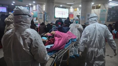 In this photo taken on January 25, 2020, medical staff wearing protective clothing to protect against a previously unknown coronavirus arrive with a patient at the Wuhan Red Cross Hospital in Wuhan. - The number of confirmed deaths from a viral outbreak in China has risen to 54, with authorities in hard-hit Hubei province on January 26 reporting 13 more fatalities and 323 new cases. 1196292480