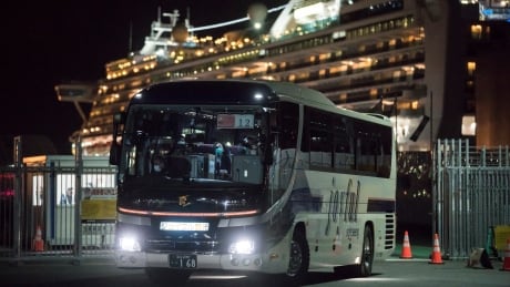 YOKOHAMA, JAPAN - FEBRUARY 19: A bus carrying passengers who will take the flight chartered by the government of the Hong Kong Special Administrative Region of the People's Republic of China drives past the quarantined Diamond Princess cruise ship docked at the Daikoku Pier on February 19, 2020 in Yokohama, Japan. About 500 passengers who have tested negative for the coronavirus (COVID-19) were allowed to disembark the cruise ship on Wednesday after 14 days quarantine period as at least 542 passengers and crew onboard have tested positive for the coronavirus. Including cases onboard the ship, 615 people in Japan have now been diagnosed with COVID-19 making it the worst affected country outside of China. 1207255252