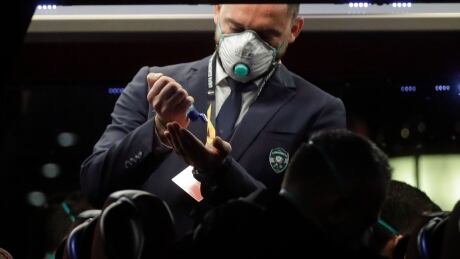 A Bulgarian soccer team Ludogorets staffer disinfects his hands as he stands on a coach bus heading to the San Siro stadium Milan, Italy, Thursday, Feb. 27, 2020. Ludogorets is playing Italian club Inter Milan in a Europa League soccer match on Thursday that is scheduled to go ahead in an empty stadium due to the coronavirus outbreak. Italy Soccer Virus Outbreak