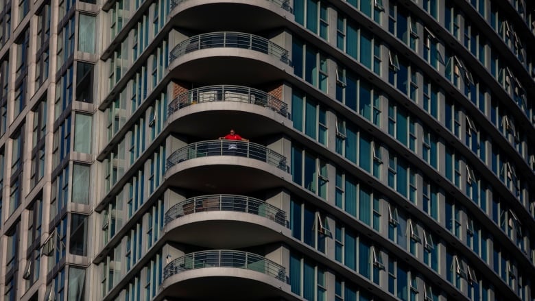 A man in a condo tower watches the sunset in downtown Vancouver on Friday. Advocacy groups have called for a moratorium on rent payments and evictions for the duration of the COVID-19 pandemic. (Ben Nelms/CBC)