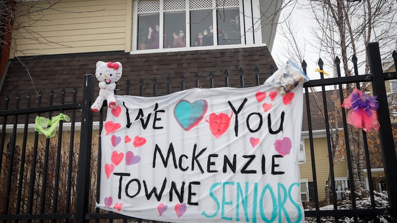 A homemade "we love you Mckenzie Towne seniors" sign hangs on a fence. 