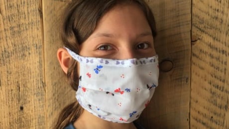 Pikssii Crowshoe, 11, models a mask sewn by the women of the Pincher Creek Hutterite Colony. A group of volunteers at the colony is sewing masks to distribute to Indigenous communities and health-care workers in southern Alberta. Hutterite masks