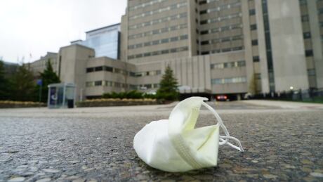 A discarded hospital-issue surgical mask lays on the asphalt on Windemere Road outside University Hospital in London, Ont. covid london hospital mask