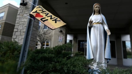 A message thanking health-care workers is seen beside a statue of Mary outside the Madonna Care Community in Ottawa, a long-term care facility where more than 40 residents have died of COVID-19. COVID Ont 20200503