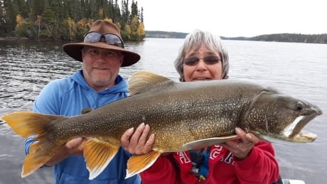 Guests at Kenanow Lodge on Kississing Lake hoist up a lake trout. Guests at Kenanow Lodge hold up lake trout