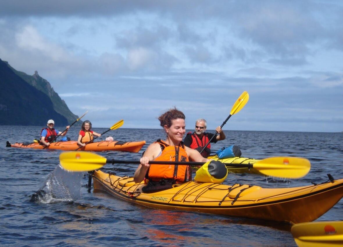 People kayaking with mountains on coastline
