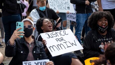 A protester holds a sign calling for justice for missing and murdered Indigenous women at a protest in Vancouver. Anti-racism protest