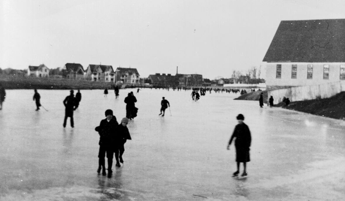 A black and white photo of Government Pond in Charlottetown. It is frozen over and many people can be seen skating.