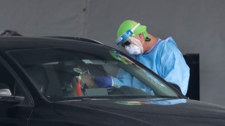 A healthcare worker takes a swab sample from a driver at a drive-through COVID-19 testing site outside Hard Rock Stadium, Wednesday, July 8, 2020, in Miami Gardens, Fla. Florida is one of the nation's hot spots for coronavirus. Virus Outbreak Florida