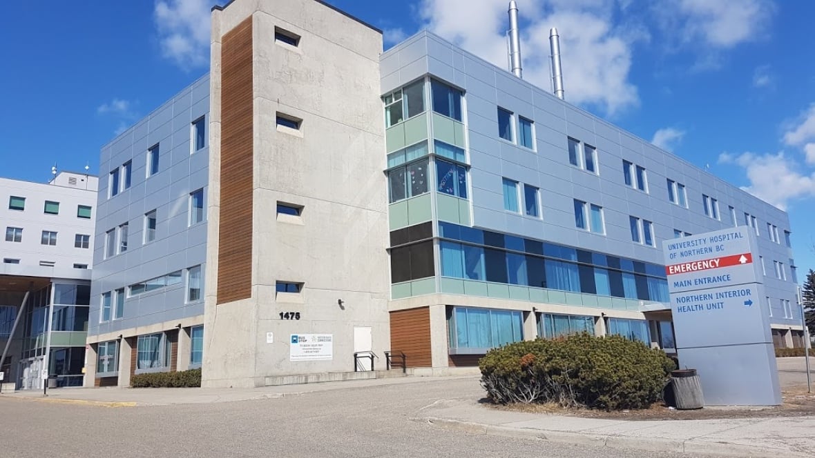 Edificio azul y marrón con dos capas de ventilación corta en pequeñas ventanas y techo. Aparte del norte de BC. El hospital universitario tiene una señal de