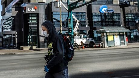 A pedestrian wearing a mask walks down the empty streets of downtown Edmonton on March 22. Mandatory mask bylaws took effect in both Calgary and Edmonton on August 1. COVID Alta 20200713