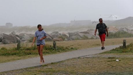 People are caught in a rain shower as Tropical Storm Isaias approaches in Kure Beach, N.C., Monday, Aug. 3, 2020. Tropical Weather North Carolina