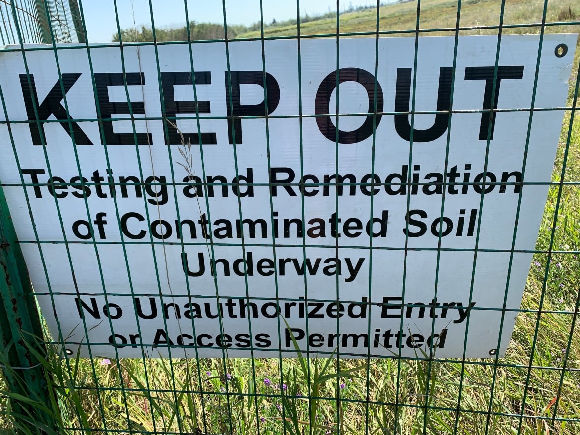 A "keep out" sign on a blue fence.