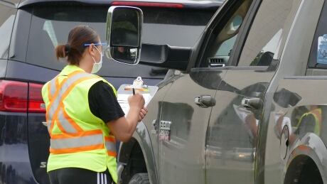 An employee wears a face mask as they talk to a person inside their truck at a COVID-19 drive-thru test site on Main Street in Winnipeg. Covid test site. Mpi Main Street
