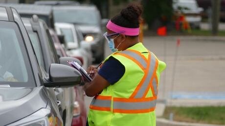 An employee holds a clipboard while talking to someone through the window of their vehicle at a drive-thru COVID-19 test site in Winnipeg. As of Thursday, 163 of the province's 360 active cases of the illness were in the Winnipeg health region. Winnipeg COVID drive thru test site