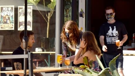 Servers deliver drinks to people sitting on a patio at Brothers Brewing in downtown Guelph. Guelph patio COVID-19 mask beer