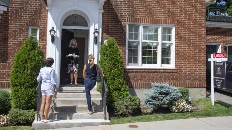 A real estate agent wearing a protective mask greets viewers outside a home for sale in Montreal, Quebec, Canada, on Wednesday, Aug. 19, 2020. Home sales in metropolitan Montreal jumped 46% in July compared with the same month in 2019 following a two-month lockdown of the economy. Photographer: Christinne Muschi/Bloomberg MONTREAL HOUSING REALTOR COVID MASK