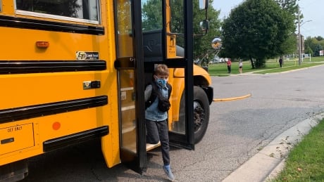 A child steps off a school bus on Tuesday in London, Ont. Child stepping off bus