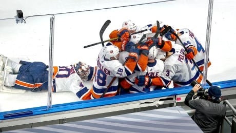 New York goalie Semyon Varlamov, left, slides across the ice to join his teammates after Jordan Eberle's double-OT goal secured the Islanders' 2-1 win over the Tampa Bay Lightning in Game 5 of their second-round playoff series. varlamov-semyon-091520