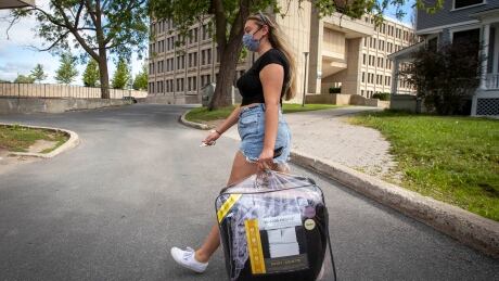 Sarah Mattioli brings some of her belongings into residence during Queen's University's move-in day in Kingston, Ont., on Tuesday Sept. 1, 2020. COVID-19 mask