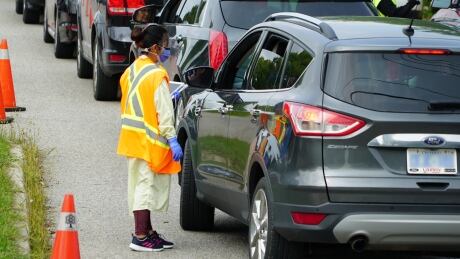 A healthcare worker speaks to someone looking for a COVID-19 test through their car window outside the assessment centre at the Oakridge Arena. testing at oakridge covid assessement centre in london