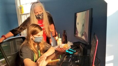 Walker Housell sits at his computer with his mother Therese overlooking him. The nine-year-old started fifth grade Wednesday — but the virtual learning environment already has him missing the social aspects of in-class instruction. wdr Walker Therese Housell