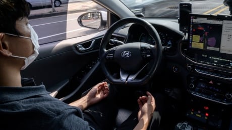 a safety driver sitting behind the wheel of a Rideflux 'self-driving' car in Jeju on May 28, 2020. In a workshop that blends a corporate office with a tool-packed garage, South Korean company Rideflux are looking to take on the multi-billion-dollar giants of Uber, Tesla and Google parent Alphabet with a self-driving car of their own. Their modified Hyundai Ioniq, festooned with cameras and proximity sensors, is the first autonomous vehicle to go into regular service on public roads in the country. 1217203613