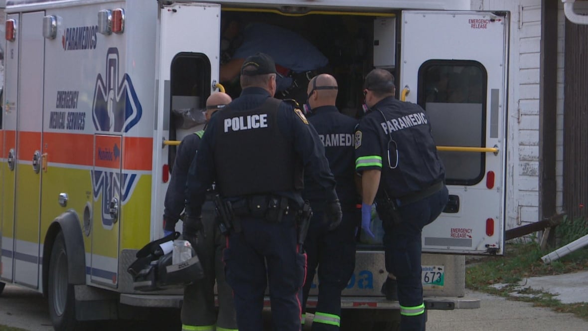 group of police officers crowd around an ambulance