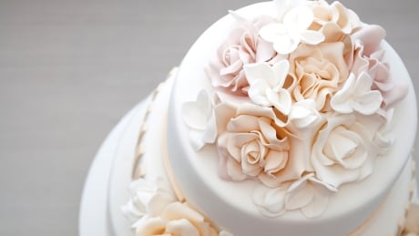 Three-tiered white wedding cake decorated with flowers from mastic on a white wooden table. Picture for a menu or a confectionery catalog. Top view.; Shutterstock ID 732154714 Wedding cake