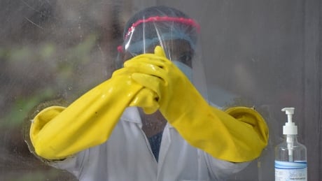 TOPSHOT - A health worker waits to collect swab samples from residents to test for the Covid-19 coronavirus at a sample collection centre in Hyderabad on October 19, 2020. (Photo by NOAH SEELAM / AFP) (Photo by NOAH SEELAM/AFP via Getty Images) 1229162097