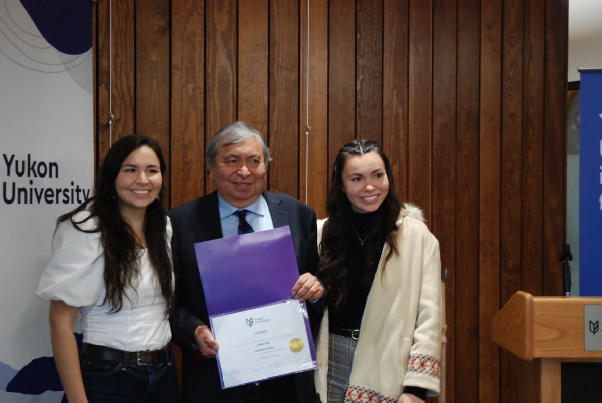 Two Indigenous women flank an Indigenous man, all of whom are beaming.
