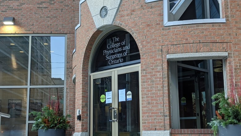 A brick building that says "College of Physicians and Surgeons of Ontario" on a window above a door.