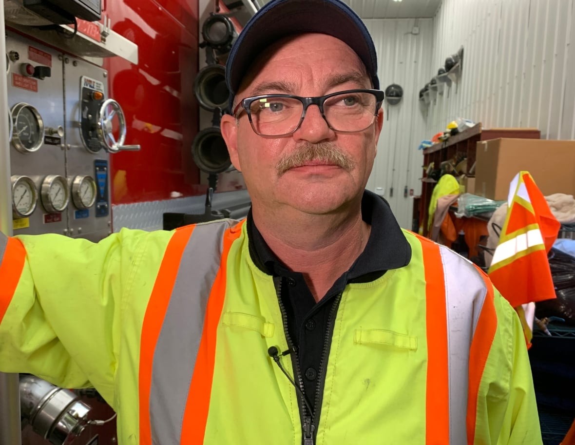 Man in glasses and hat wearing a reflective vest.