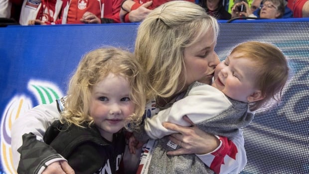 A woman holds her two children.