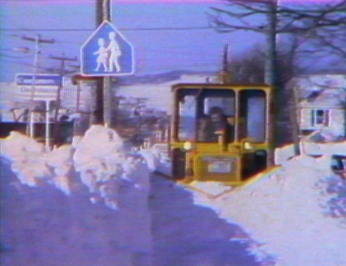 machine clears snow on sidewalk on a sunny day