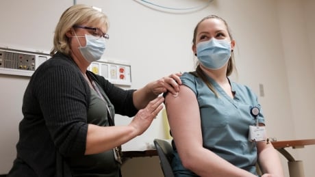 Debbie Frier, registered nurse, left, injects Leah Sawatsky, an emergency room nurse, right, with the Pfizer-BioNTech COVID-19 vaccine at the Regina General Hospital in Regina on Tuesday, Dec. 15, 2020. SK VACCINATION 20201215