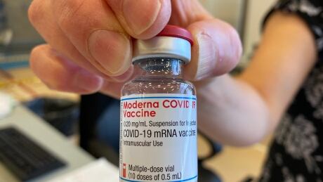 See close up of hand holding vaccine vial. Vaccine Clininc in Thompson Moderna Vaccine