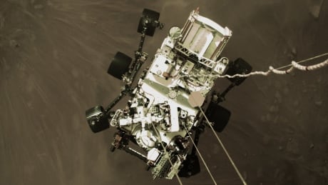This Thursday, Feb. 18, 2021 photo provided by NASA shows the Perseverance rover lowered towards the surface of Mars during its powered descent. Mars Landing