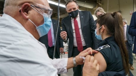 Quebec Premier François Legault watches a woman get her COVID-19 vaccine at a clinic in Montreal's Olympic Stadium on Tuesday. COVID Que 20210223
