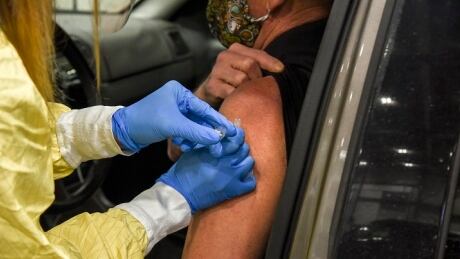 A 64-year-old receives a dose of AstraZeneca-Oxford's COVID-19 vaccine on Monday at Regina's mass drive-thru clinic. regina drive thru clinic