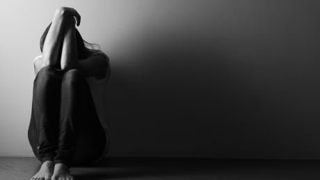 Teenage girl sitting alone on the floor in the dark room. Black and white photo. Depression concept. Adobe Stock - Standard Image