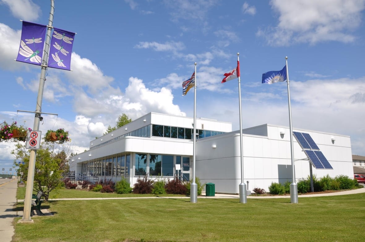 White building with flag poles in front of it.